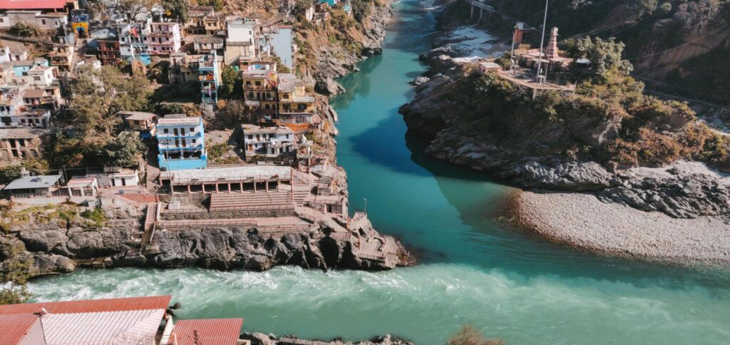 Colorful boats anchored along the ghats of Prayagraj on the Ganges River at sunset with historic buildings in the background