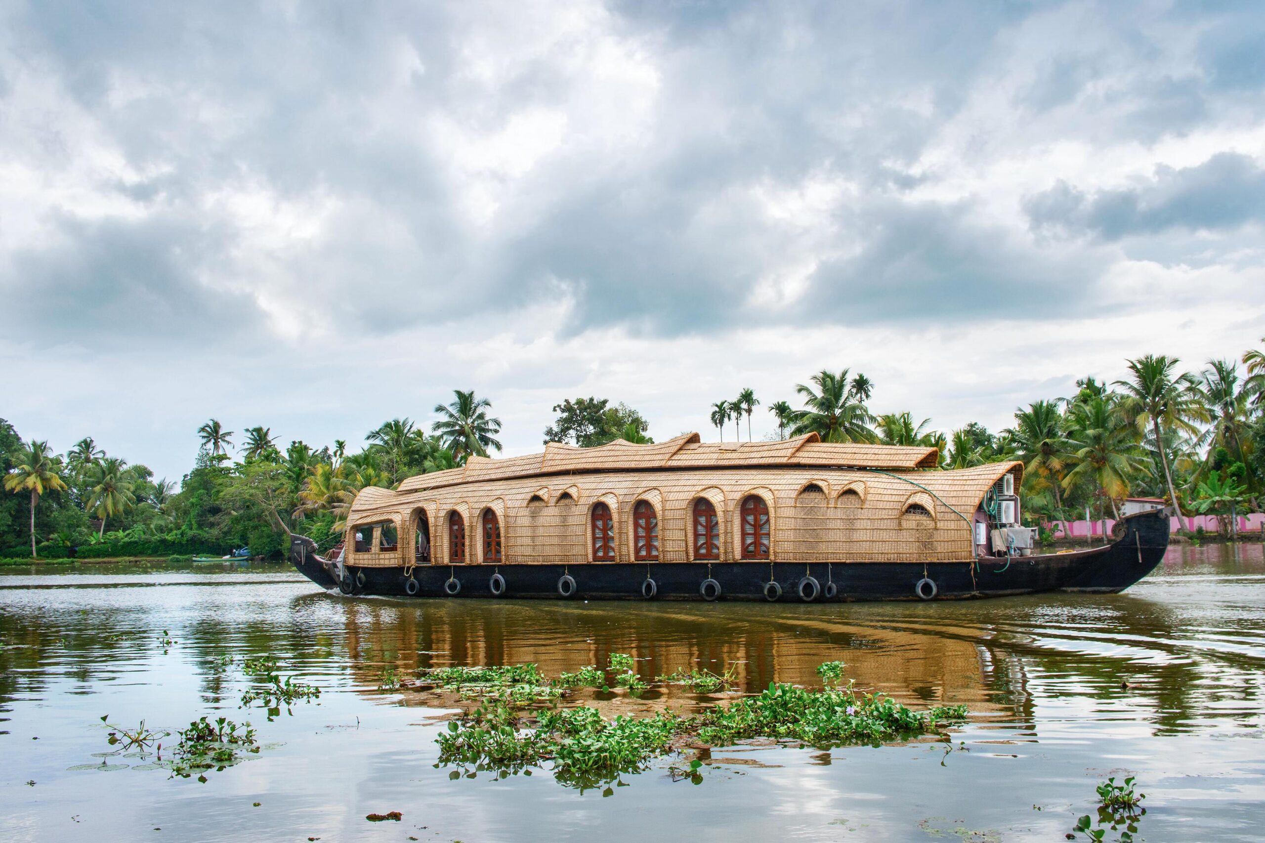 Elegant houseboat floating on calm backwaters surrounded by palm trees in Kerala, India