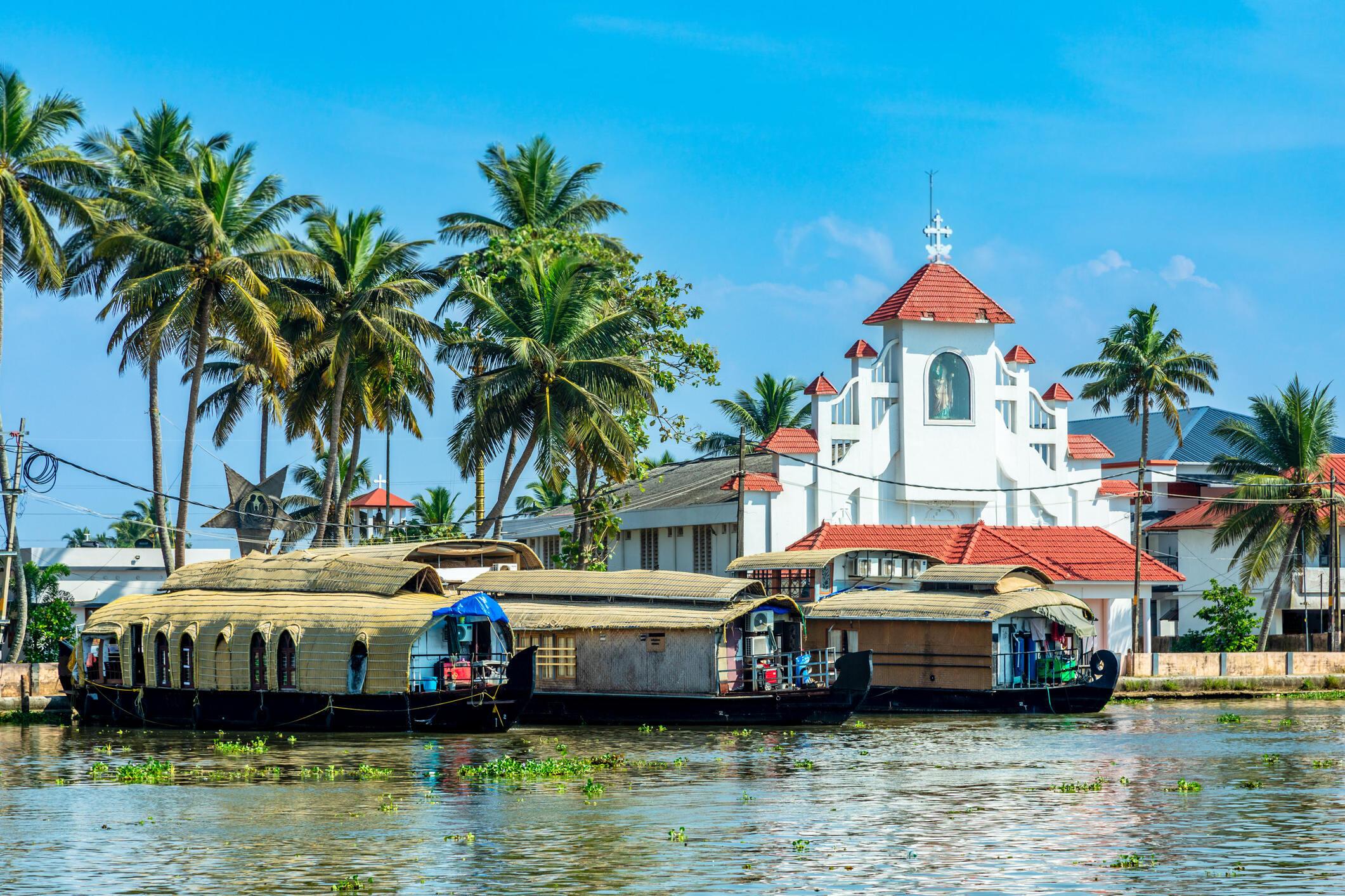 Traditional wooden houseboat cruising through lush green backwaters in Kerala, India