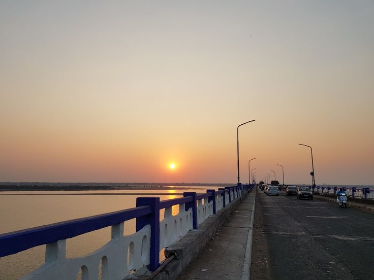 Sunset view from a road bridge in Rajahmundry with orange skies and street lamps lining the pathway