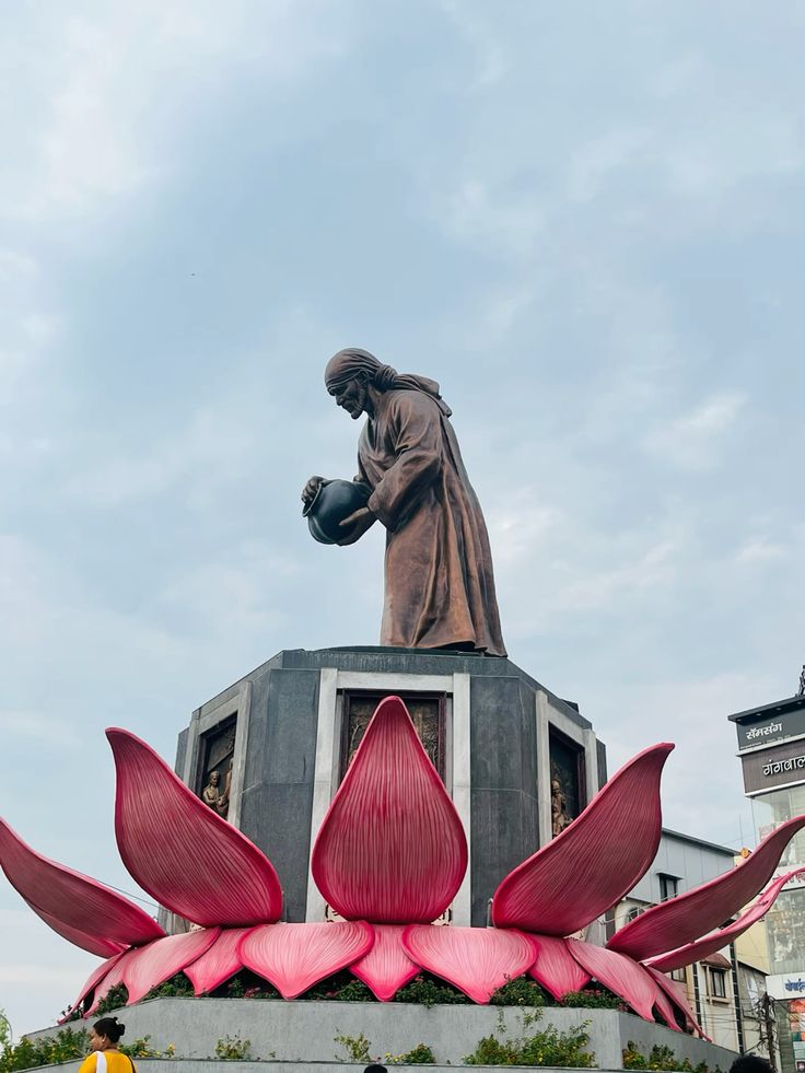Statue of Sai Baba in Shirdi atop a pedestal with architectural detailing