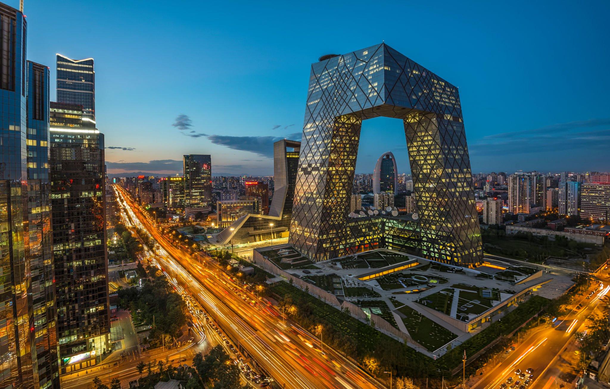 Night view of Beijing skyline with illuminated CCTV Headquarters building and busy city streets