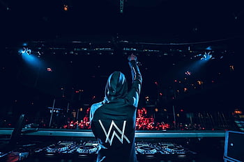 DJ Alan Walker performing live on stage with signature hoodie and logo during a music concert.